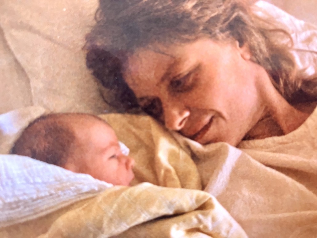 Mutter ihr Neugeborenes liebevoll anschauend.